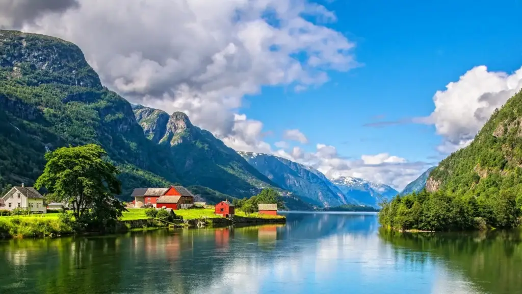 Village beside a calm Norwegian fjord below green mountains