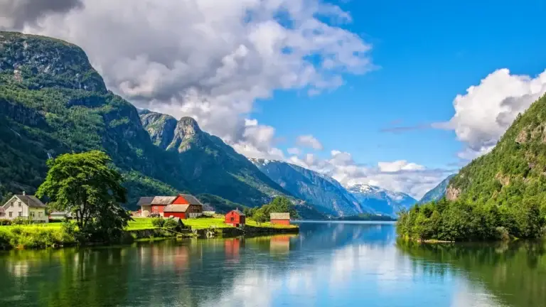 Village beside a calm Norwegian fjord below green mountains