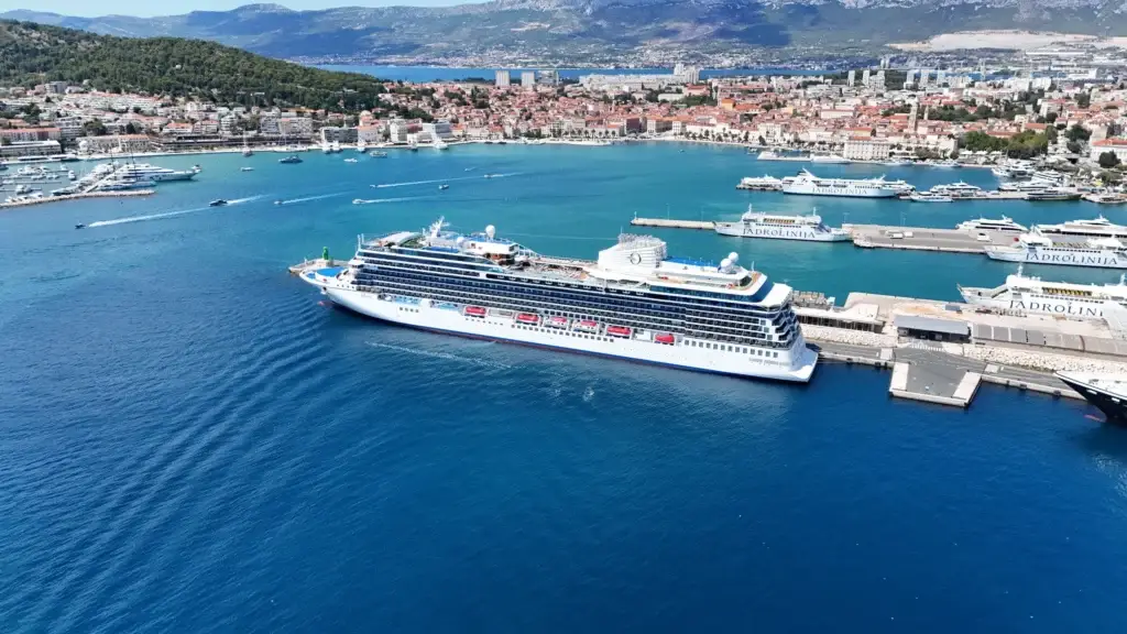 Oceania Cruises ship docked at a coastal harbor town