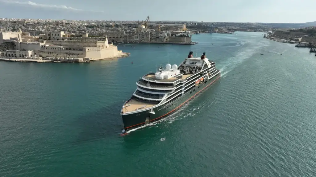 Seabourn ship sailing past a historic harbor city