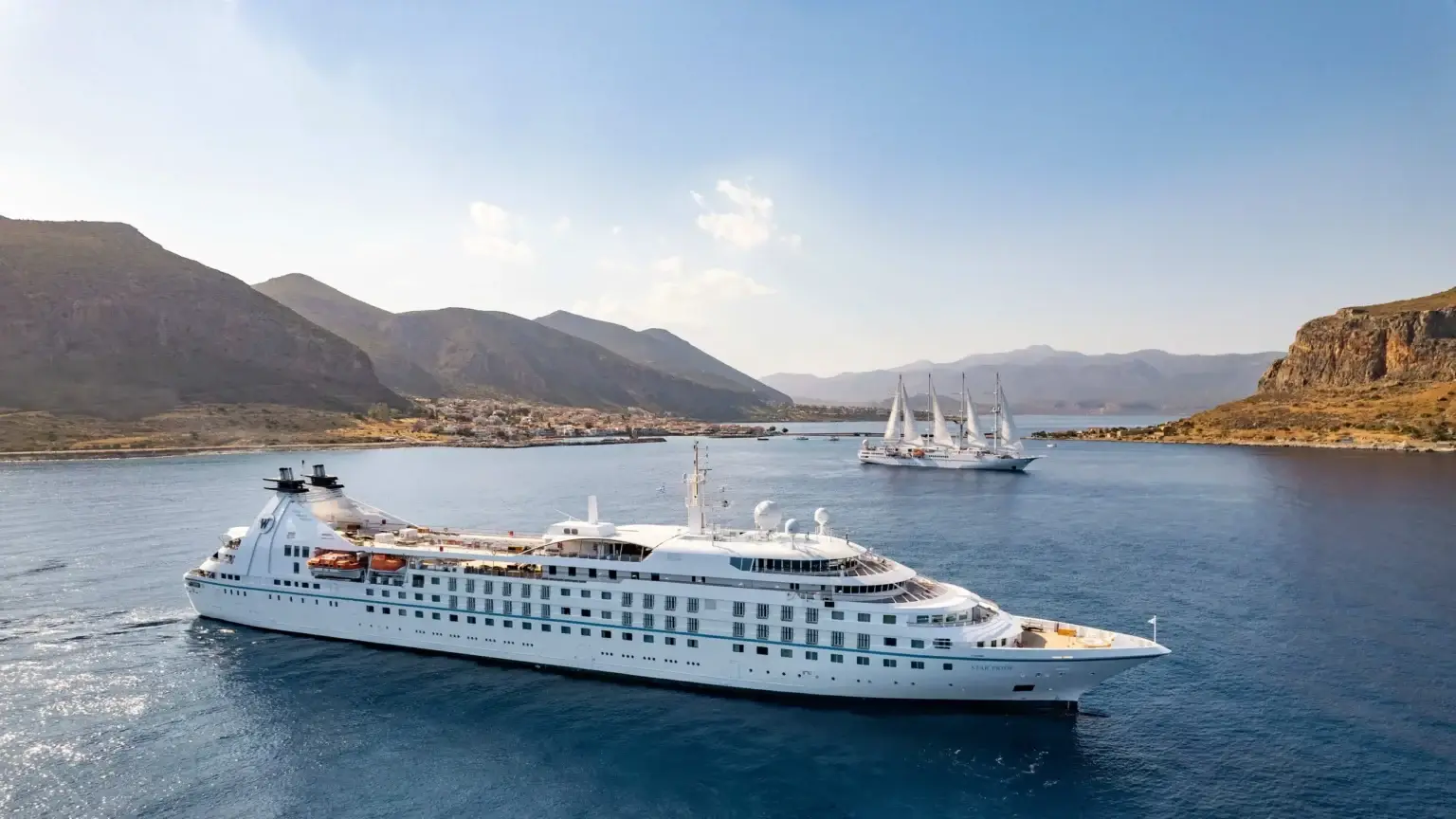 Windstar ship cruising past rugged coastal cliffs
