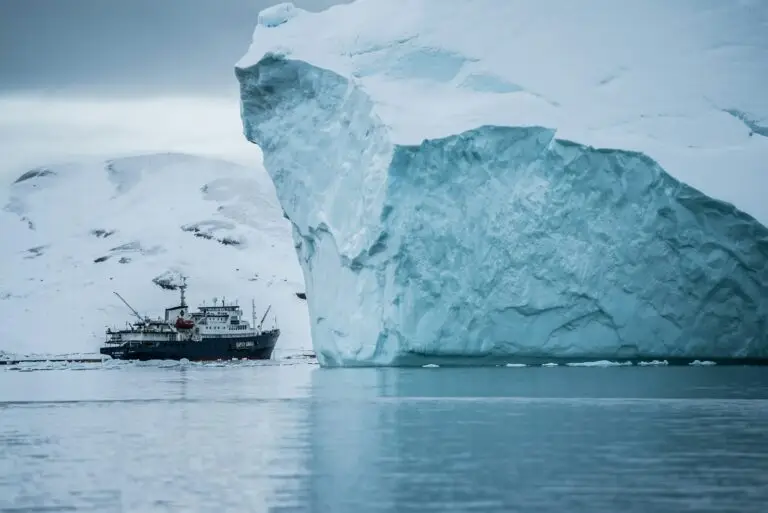 Expedition ship sailing beside an iceberg