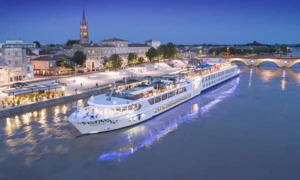 River cruise ship docked along a riverfront town at dusk